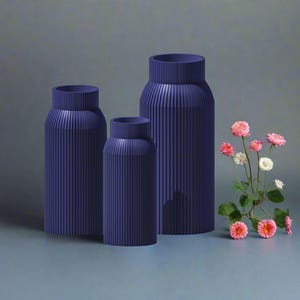 May include: Three blue ceramic vases with a ribbed texture. The vases are arranged in a row from largest to smallest. The largest vase is on the left, the smallest vase is on the right, and the middle vase is in the center.