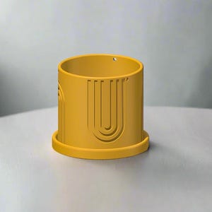 May include: A yellow ceramic planter with a geometric design. The planter has a wide base and a cylindrical shape.