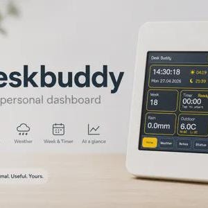 May include: A white digital desk display labeled Deskbuddy with a screen showing time, date, weather, week, timer, and outdoor temperature. The interface includes icons for time, weather, calendar, and charts, with the text Minimal. Useful. Yours.