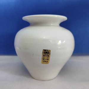 Könnte beinhalten: Weiße Keramikvase mit einem goldenen Etikett mit der Aufschrift "tiko gouda".