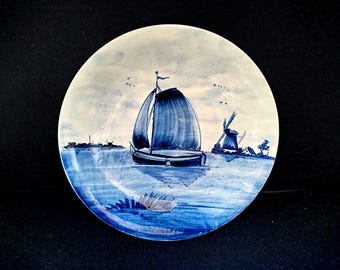 Plato antiguo de Delft azul pintado a mano que representa un velero tradicional holandés.