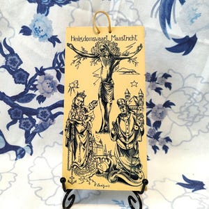 Może przedstawiać: Wizerunek religijny w stylu vintage z czarno-białą ilustracją sceny ukrzyżowania, kobiety trzymającej dziecko i mężczyzny trzymającego laskę. Wizerunek jest na żółtym tle i zawiera tekst "Heiligdomsvaart Maastricht" u góry.