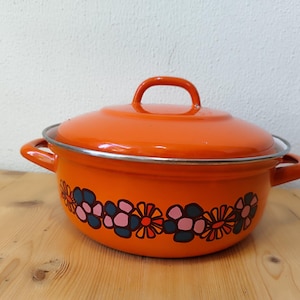 May include: Orange enamel pot with a lid and two handles. The pot has a floral design in shades of pink, blue, and orange.