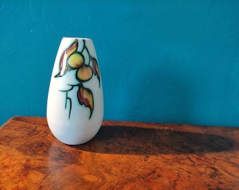 May include: A white ceramic vase with a teardrop shape and a floral design in shades of yellow, red, and green.