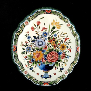 Könnte beinhalten: Ein weißer Keramikteller mit grünem und goldenem Rand. Der Teller zeigt ein handgemaltes Blumenmuster mit einem Strauß bunter Blumen in einer blauen Vase.