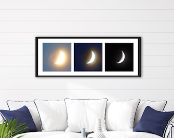 May include: A white couch with blue pillows in a living room setting. A framed print of three crescent moons in different phases hangs on the wall above the couch.