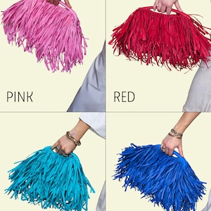 May include: Four fringed handbags in pink, red, aqua, and royal blue. Each bag has a handle and is held by a person. The colours are labelled below each bag. The bags are made of a fringed material.