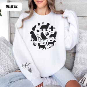 May include: White sweatshirt with a black design of various animals, paw prints, and veterinary symbols. The text "Chloe" is on the sleeve with a veterinary symbol.
