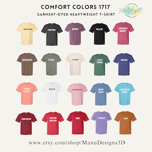 Op de afbeelding: Een display van Comfort Colors 1717 garment-dyed heavyweight t-shirts in diverse kleuren, waaronder Banana, Pepper, Berry, Black en Crunch Berry. Elk shirt heeft de kleurnaam in het wit gedrukt. De Etsy shop URL is ook zichtbaar.