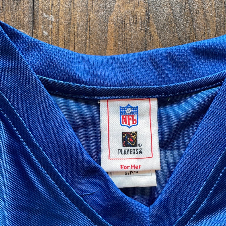May include: A blue NFL Players Inc. jersey tag with the text "For Her" and "S/P/P".