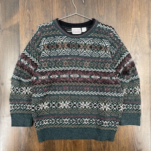 May include: A green, burgundy, and white patterned sweater with a crew neck. The sweater has a repeating geometric design and the label reads "Tip Top". The sweater is hanging on a metal hanger.