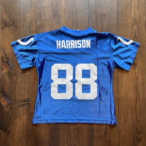 May include: Blue football jersey with white lettering. The jersey has the name "HARRISON" and the number "88" on the back.