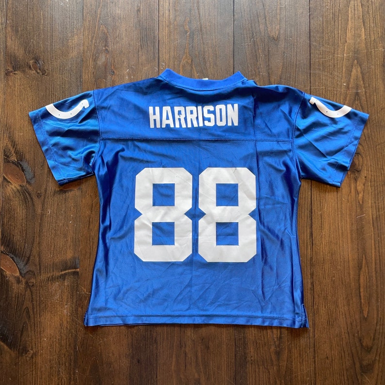 May include: Blue football jersey with white lettering. The jersey has the name "HARRISON" and the number "88" on the back.