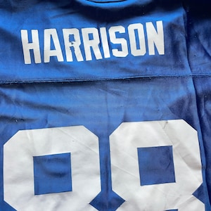 May include: A blue football jersey with the name "HARRISON" and the number "98" printed on the back in white.