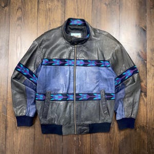 May include: A black leather jacket with a blue and purple geometric pattern on the sleeves and torso. The jacket has a zip fastening and a stand-up collar.
