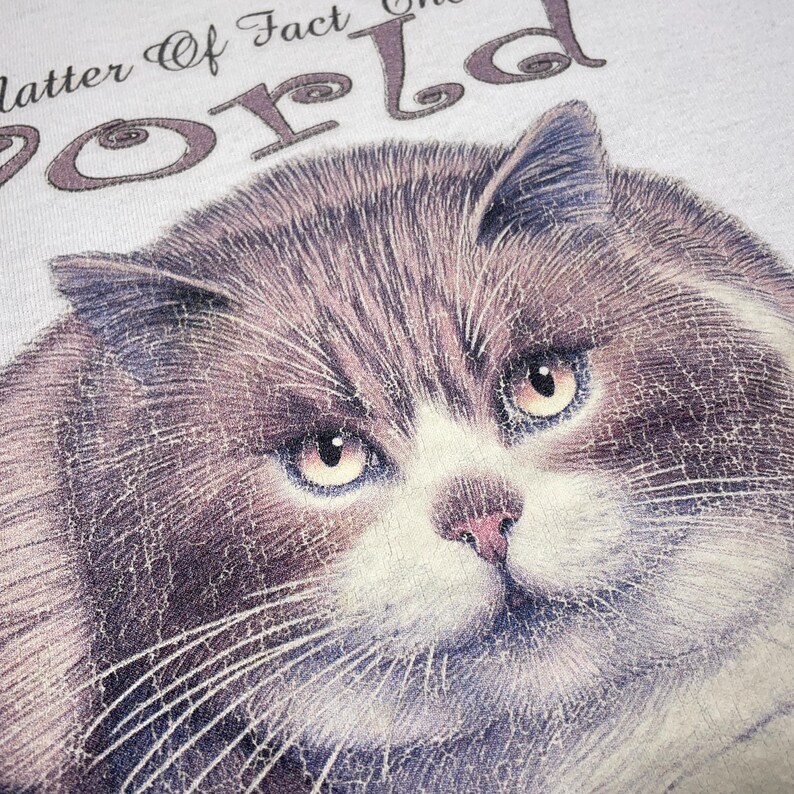 May include: A white t-shirt with a gray cat illustration and the text "As a matter of fact, the world revolves around me."