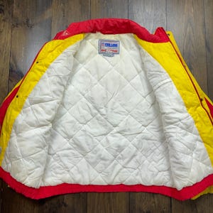 May include: Red and yellow reversible jacket with a white quilted lining. The jacket has a zip closure and a Pro Line logo on the inside.