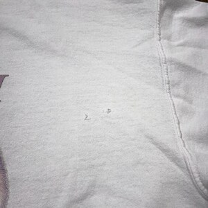 May include: White t-shirt with a small hole in the fabric.