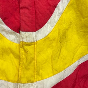 May include: A red, white and yellow jacket with a zip fastening. The jacket has a geometric pattern.