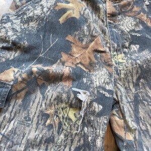 May include: Camouflage print pants with a small tear in the fabric. The pants are made of a soft, comfortable material and have a relaxed fit.