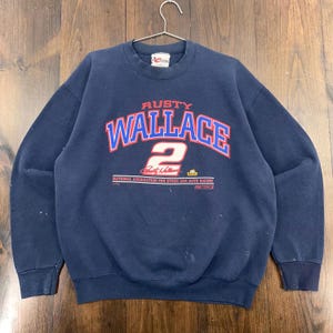 May include: A navy blue sweatshirt with the name "RUSTY WALLACE" in red and blue arched lettering, and the number "2" below. The sweatshirt includes text for the National Association for Stock Car Auto Racing.