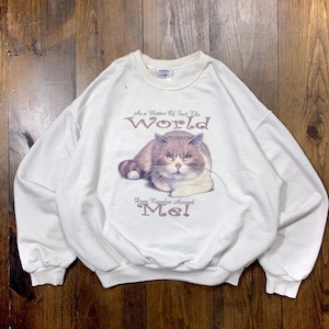 May include: White sweatshirt with a brown and white cat graphic. The text on the shirt reads "As a matter of fact the world does revolve around me!"