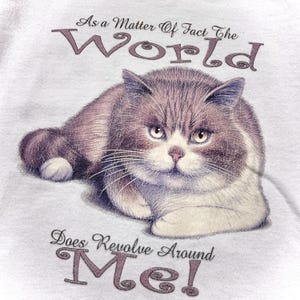 May include: A white t-shirt with a cartoon cat and the text "As a matter of fact the world does revolve around me!"
