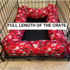 May include: Red and white dog-themed crate liner with a black and white bone pattern. The liner is placed inside a black metal dog crate. The text "FULL LENGTH OF THE CRATE" is visible in the image.