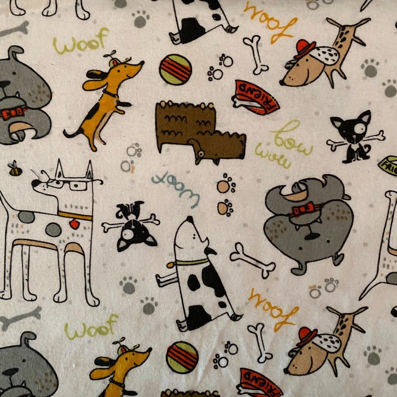 May include: White fabric featuring a repeating pattern of cartoon dogs in various poses. The dogs are in shades of grey, brown, and black, with accents of yellow and red. Scattered around are bones, paw prints, and the word "Woof".