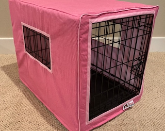 May include: Pink polka dot dog crate cover with a white trim. The cover has a window on the side and the text "Hound Heaven" is on the bottom of the crate.