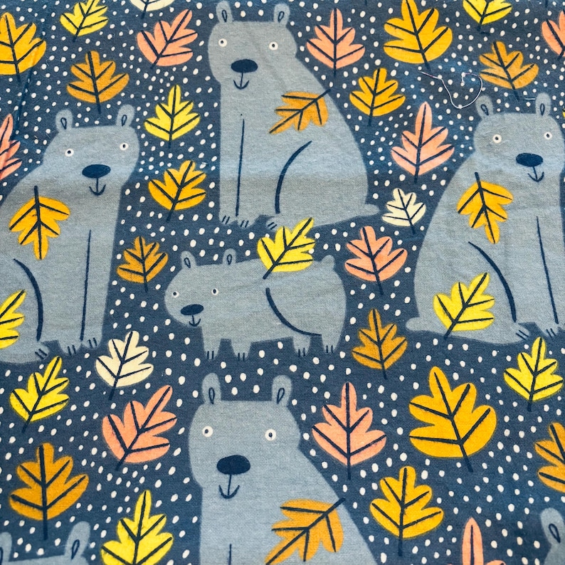 May include: A textile design with light grey bears and colourful autumn leaves on a dark blue backdrop with white polka dots. The bears are in different poses, and the leaves are in shades of yellow, orange, and pink.