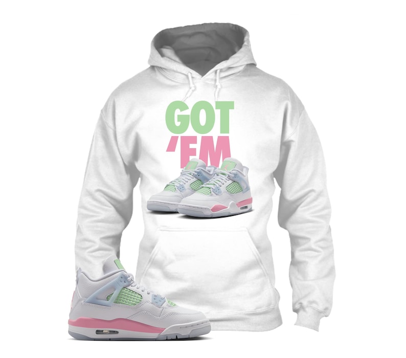 May include: White hoodie with the text "GOT 'EM" in green and pink. The hoodie features an image of trainers in white, pink, and green. A pair of trainers in the same color scheme is in the foreground.