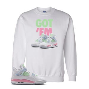 May include: White sweatshirt with the text "GOT 'EM" in green and pink. The sweatshirt features an image of sneakers in pastel colours. A single sneaker in the same style is in the foreground.