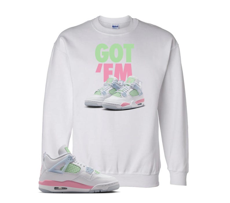 May include: White sweatshirt with the text "GOT 'EM" in green and pink. The sweatshirt features an image of sneakers in pastel colours. A single sneaker in the same style is in the foreground.