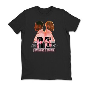 May include: Black t-shirt featuring a graphic of two men in pink suits, back-to-back. The text "THE R&B TOUR" is above the men, with "RAYMOND & BROWN" in a pink rectangle below. Signatures are visible.