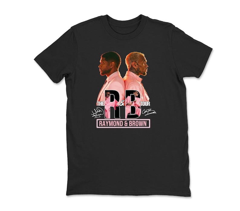 May include: Black t-shirt featuring a graphic of two men in pink suits, back-to-back. The text "THE R&B TOUR" is above the men, with "RAYMOND & BROWN" in a pink rectangle below. Signatures are visible.