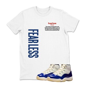 May include: White t-shirt with the word "FEARLESS" in blue vertical text and the definition of "fearless" in red. A pair of blue and white sneakers are at the bottom of the image.