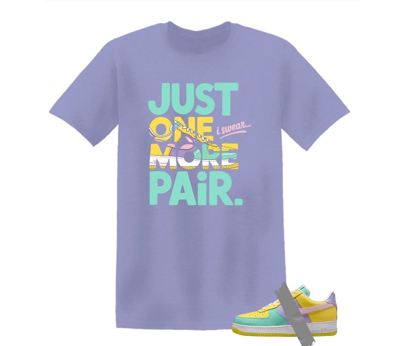 May include: A light purple t-shirt with the text "JUST ONE MORE PAIR. i swear..." in teal, yellow, and white. The graphic features a colorful sneaker design. A matching sneaker is visible at the bottom.