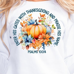 May include: White sweatshirt with a round design featuring a watercolor illustration of pumpkins, fall leaves, and flowers. The text "Enter His Gates with Thanksgiving and Praise His Name" surrounds the illustration. The text "Psalms 100:4" is below the illustration.