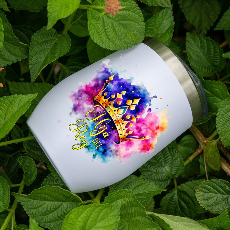 May include: White stainless steel wine tumbler with a gold crown and watercolor design. The text "Hija del Rey" is written in gold script.