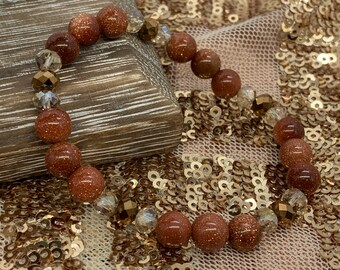 May include: A brown and gold beaded bracelet with small, round, brown beads and clear, faceted beads.