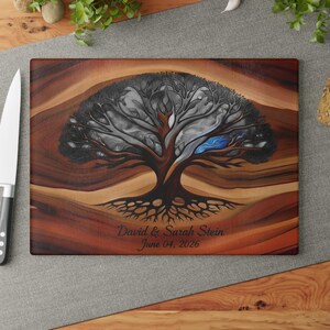 May include: A rectangular wooden cutting board featuring a dark brown wood grain background and a central illustration of a large tree with intricate branches. The text David & Sarah Stein June 04, 2026 is printed in black below the tree.