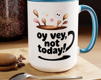 May include: White ceramic mug with a blue interior and handle. The mug features the phrase "oy vey, not today!" in black, with a coffee splash design above the text. A spoon and a macaron are next to the mug.