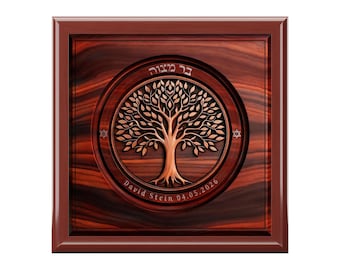 May include: A square wooden plaque with a dark reddish-brown finish featuring a circular inlay. The center displays a carved tree of life design, Hebrew text, the name David Stein, the date 04.05.2026, and two small Star of David symbols.