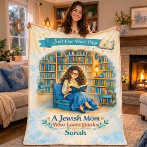 May include: A white ceramic mug with a black handle and the text "But First, Coffee" in a bold, black font. The mug is set against a blurred background, suggesting a cozy setting.