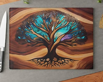 May include: A rectangular wooden cutting board featuring a central tree illustration with dark brown branches and roots set against a swirling background of vibrant turquoise, blue, and purple hues, with a white knife positioned to the left side.