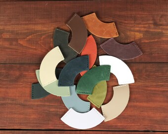 May include: A collection of arc-shaped leather pieces in various colors including tan, brown, dark green, light green, white, cream, blue, and grey. Each piece features visible stitching along the curved edges, arranged in a circular pattern.