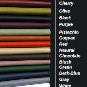 May include: A stack of fifteen rectangular leather-like items in various colors including pink, lilac, cherry, olive, black, purple, pistachio, cognac, red, natural, chocolate, blush, green, dark-blue, gray, and white, with corresponding text labels.
