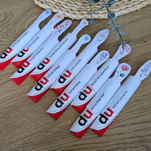 May include: A collection of white and red candy bars with floral designs and German text. Each bar has a different message, such as "You are wonderful" and "You make me happy."