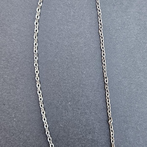 May include: A silver chain bookmark with a feather charm and a cluster of red and orange beads. The bookmark is designed to be placed in a book to mark a page. The chain is approximately 10 inches long.